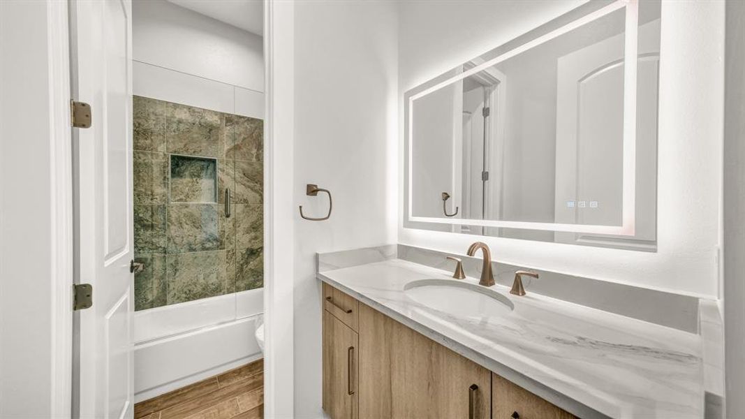 Full bathroom with bath / shower combo with glass door, hardwood / wood-style floors, vanity, and toilet