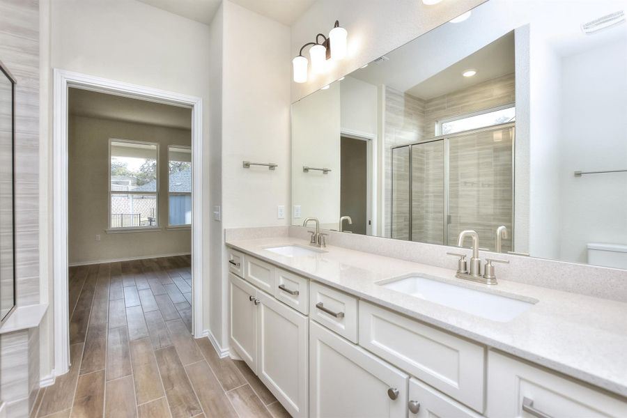 Full bathroom featuring wood tiled floor, double vanity, a shower stall, and a sink