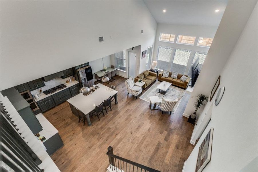 Living room with dark wood-style floors, a high ceiling, and recessed lighting