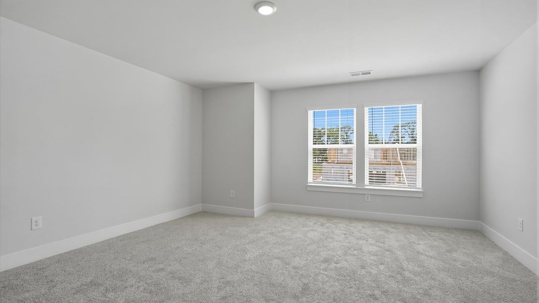 Superior comfort in this light-filled bedroom with plush carpeting and thoughtfully placed large windows at Village at Midway