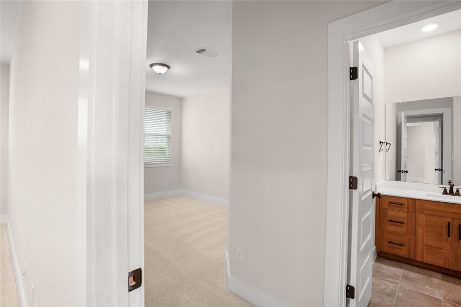 A well-lit bedroom with soft carpeting and a private adjoining bathroom offers comfort and convenience. A well-lit bedroom with soft carpeting and a private adjoining bathroom offers comfort and convenience.