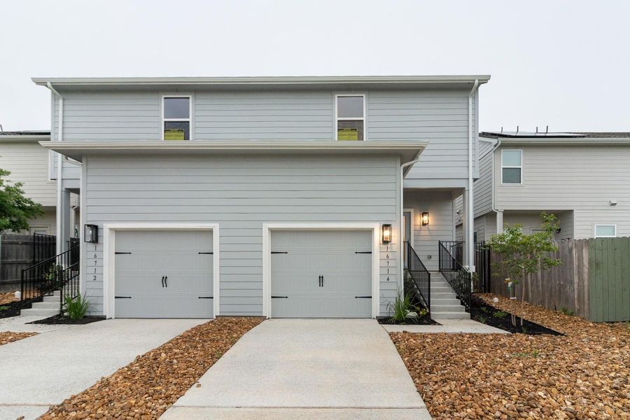The property features light-colored horizontal siding, two garage doors, and a front entry with exterior lighting