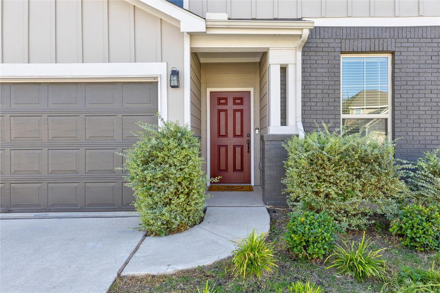 Doorway to property featuring board and batten siding, brick siding, and a garage