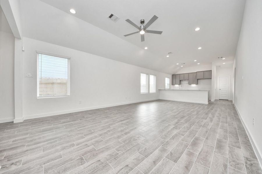 Welcome family and guests to your charming living room! With its high ceilings, recessed lighting, ceiling fan, custom paint, beautiful flooring, and large windows that let in abundant natural light, this room is perfect for gatherings.