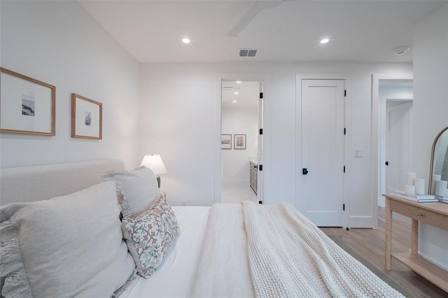 Bedroom featuring ceiling fan, ensuite bath, and light hardwood / wood-style floors