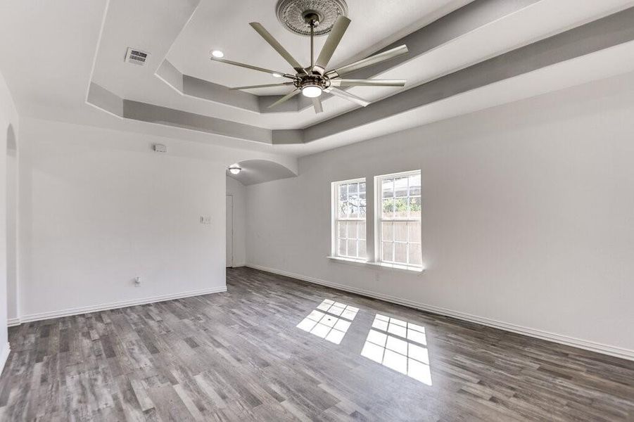 Unfurnished room with hardwood / wood-style flooring, a tray ceiling, and ceiling fan