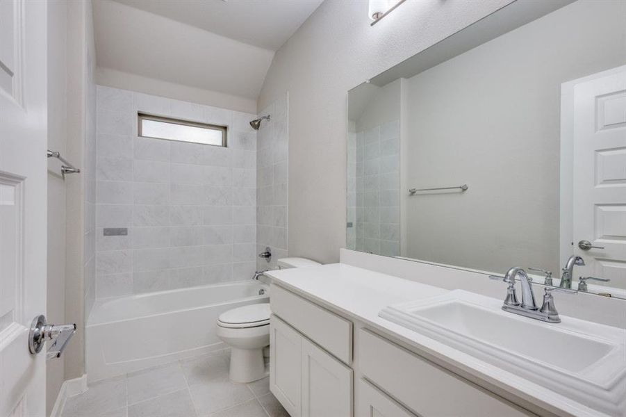 Full bathroom with bathtub / shower combination, vanity, and light tile patterned floors Full bathroom with bathtub / shower combination, vanity, and light tile patterned floors
