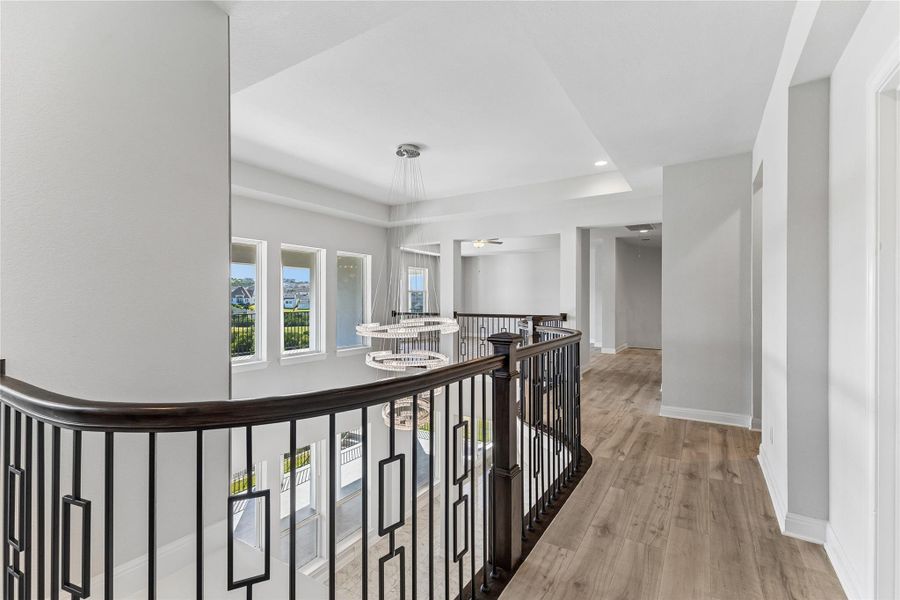 A spacious landing with light wood flooring provides an airy, illuminated pathway.