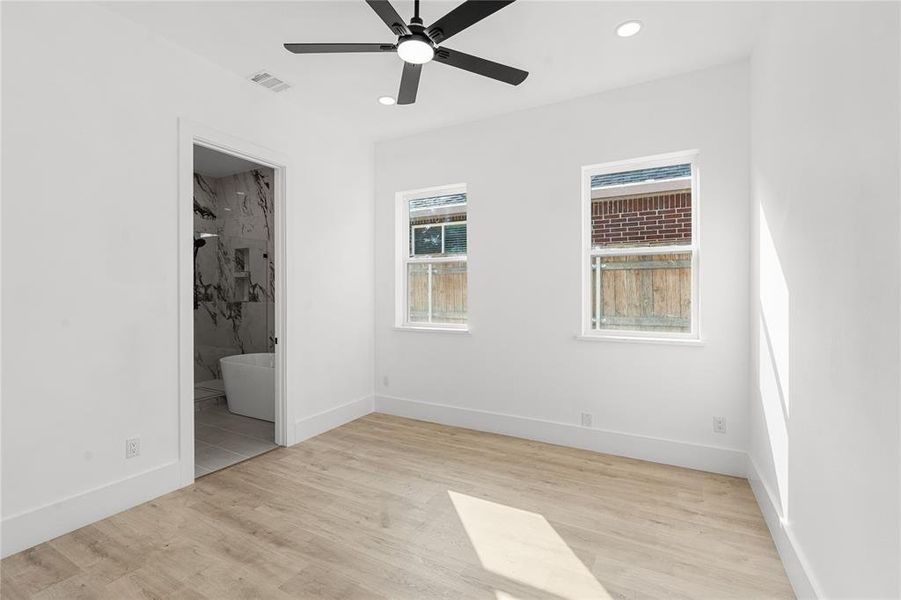 Unfurnished bedroom featuring light wood-style floors, ceiling fan, recessed lighting, and connected bathroom Unfurnished bedroom featuring light wood-style floors, ceiling fan, recessed lighting, and connected bathroom