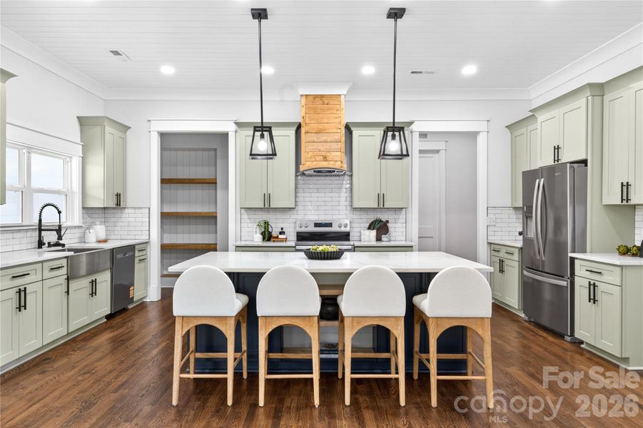 Open kitchen with quartz countertops, custom cabinetry, stainless steel appliances, oversized island, and warm wood accents that bring a modern farmhouse feel to the space.
