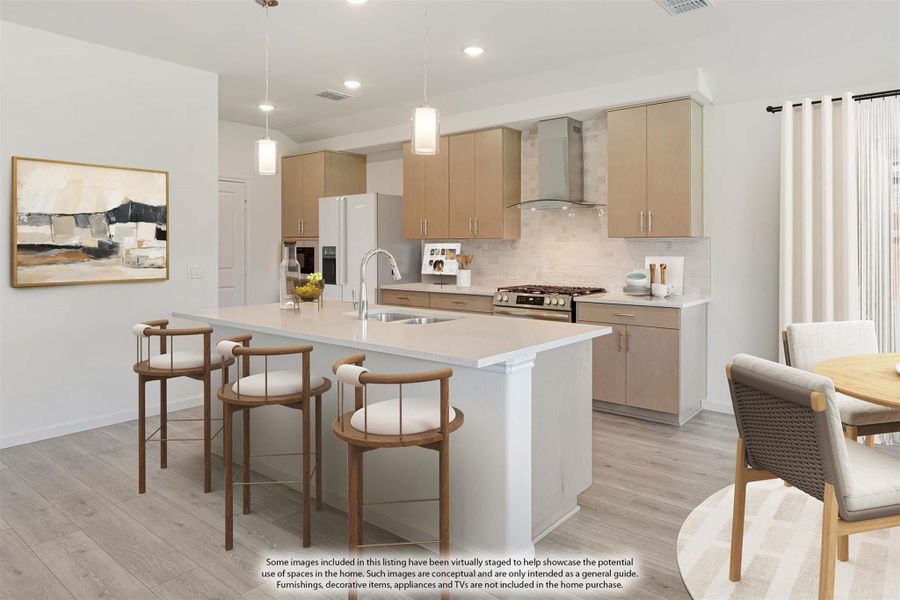 Kitchen with large island, light wood cabinets, pendant lights, and stainless steel range hood Kitchen with large island, light wood cabinets, pendant lights, and stainless steel range hood