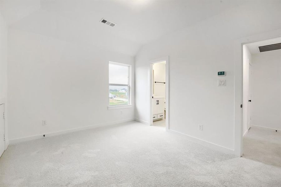 Vaulted ceiling room with light-colored carpeting, white baseboards, and a single-pane window