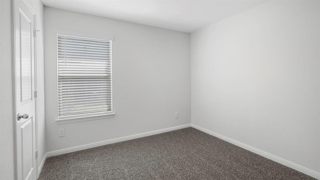 Spare room featuring baseboards and dark colored carpet