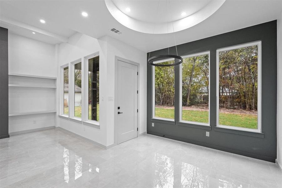 Empty room featuring a tray ceiling and a wealth of natural light