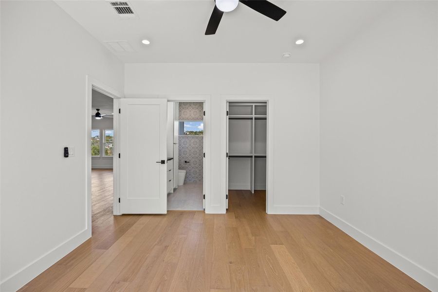 Unfurnished bedroom with a walk in closet, ensuite bath, light wood-style flooring, recessed lighting, and a ceiling fan Unfurnished bedroom with a walk in closet, ensuite bath, light wood-style flooring, recessed lighting, and a ceiling fan
