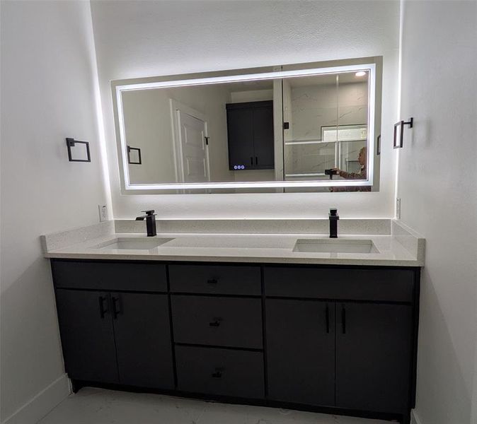 Full bathroom with a sink, baseboards, an enclosed shower, and double vanity