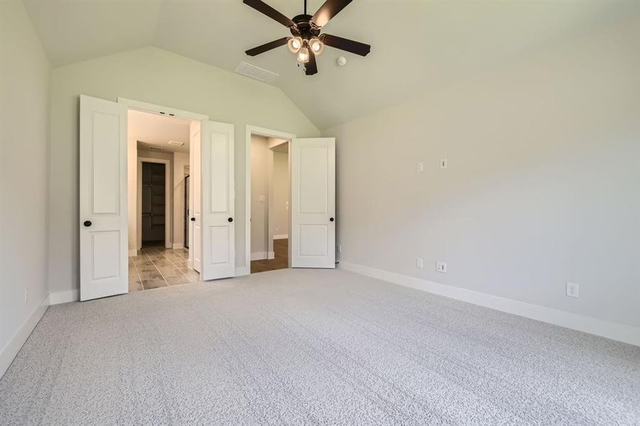 Unfurnished bedroom featuring light carpet, vaulted ceiling, and a ceiling fan Unfurnished bedroom featuring light carpet, vaulted ceiling, and a ceiling fan