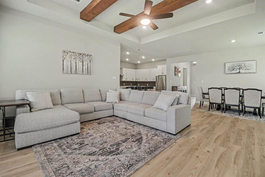 This spacious, open-concept living area features a modern design with a cozy sectional, wood beam accents, and elegant lighting. The kitchen boasts stainless steel appliances and a large dining area perfect for entertaining. This spacious, open-concept living area features a modern design with a cozy sectional, wood beam accents, and elegant lighting. The kitchen boasts stainless steel appliances and a large dining area perfect for entertaining.