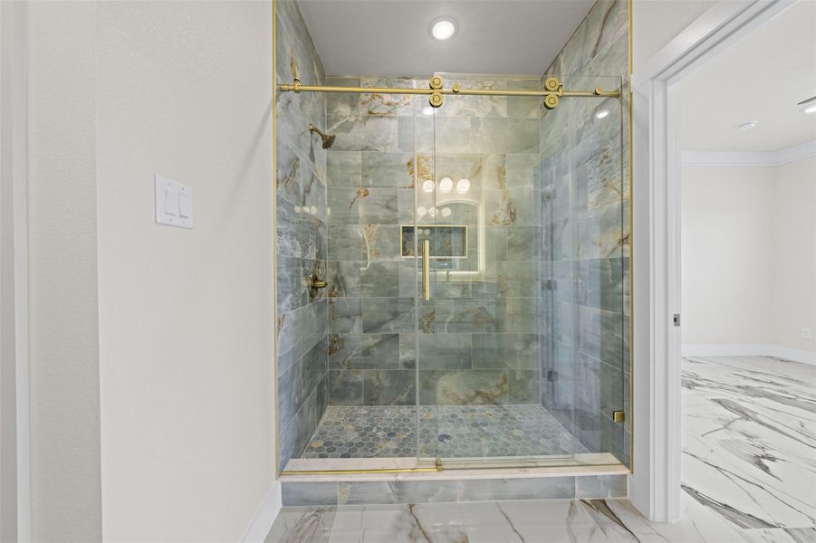 Exquisite custom tiling and brass hardware define this luxurious walk-in shower.