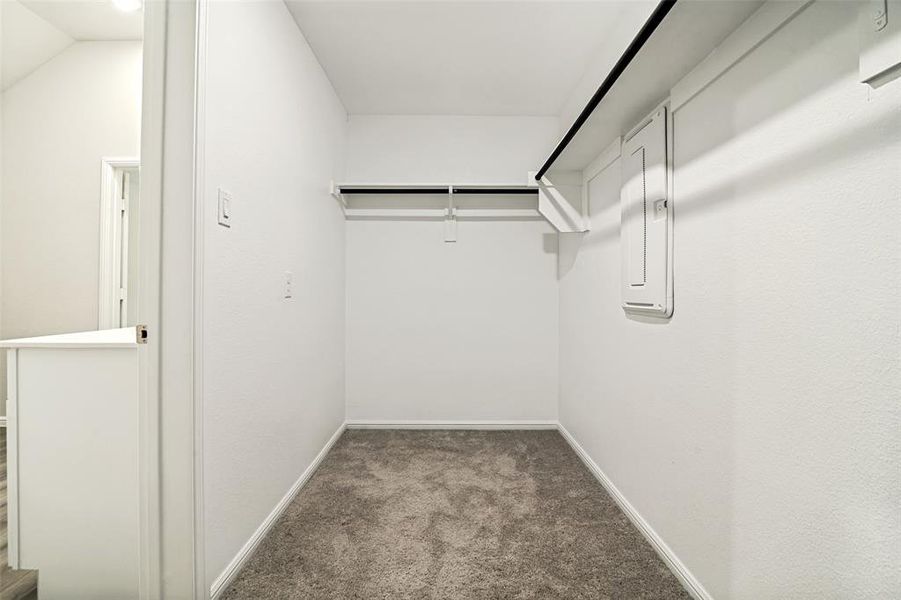 Primary walk-in closet featuring plush gray carpeting, white walls, and built-in shelving with hanging rods Primary walk-in closet featuring plush gray carpeting, white walls, and built-in shelving with hanging rods