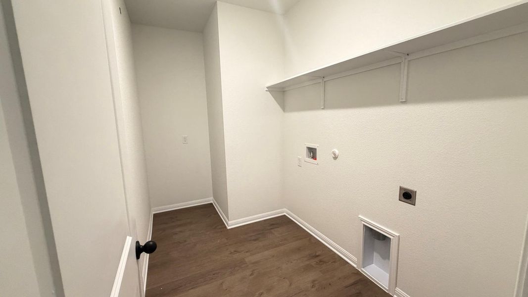 A well-appointed laundry room features a sturdy wall shelf and durable wood flooring. A well-appointed laundry room features a sturdy wall shelf and durable wood flooring.