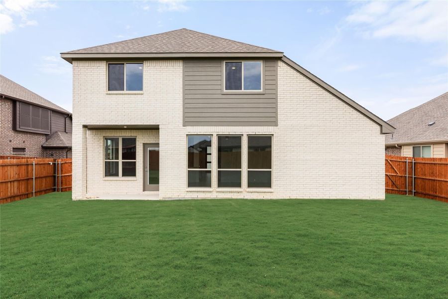 Two-story home with white brick exterior, large backyard, and wood privacy fence Two-story home with white brick exterior, large backyard, and wood privacy fence