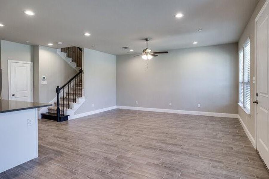 Unfurnished living room featuring a ceiling fan, plenty of natural light, stairs, light wood-type flooring, and recessed lighting