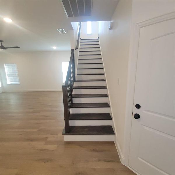 Stairs featuring ceiling fan and hardwood / wood-style floors