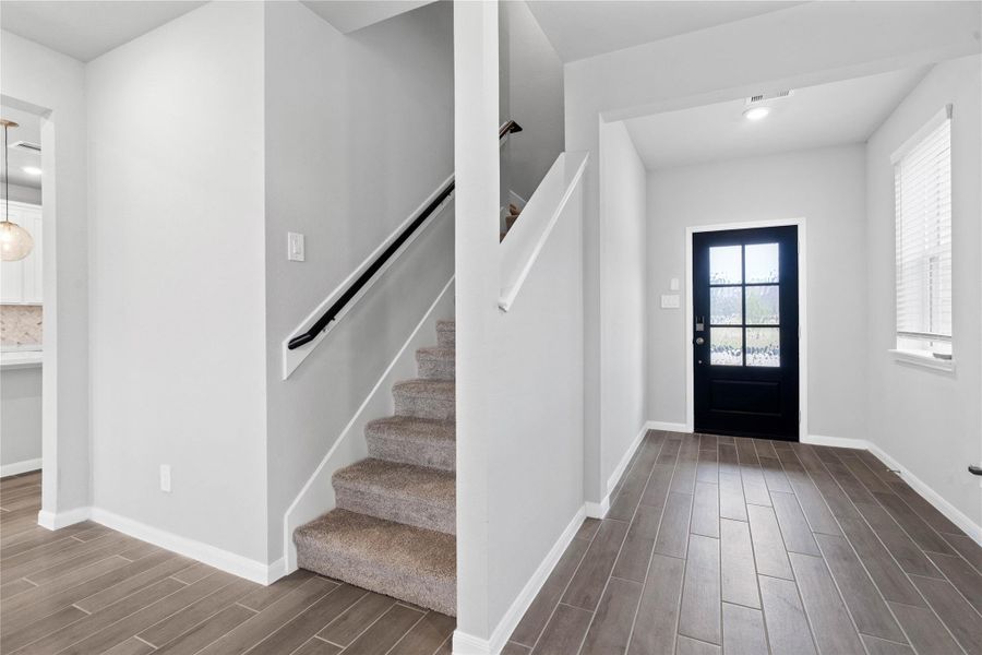 Step inside to a light-filled foyer featuring wood-look tile flooring, recessed lighting and the striking black six-lite entry door that makes a bold first statement. The space flows effortlessly towards the staircase with a sleek handrail, leading to the second floor bedrooms and bathrooms.