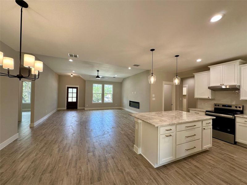 Kitchen with stainless steel range with electric cooktop, wood finished floors, ceiling fan, under cabinet range hood, and open floor plan Kitchen with stainless steel range with electric cooktop, wood finished floors, ceiling fan, under cabinet range hood, and open floor plan