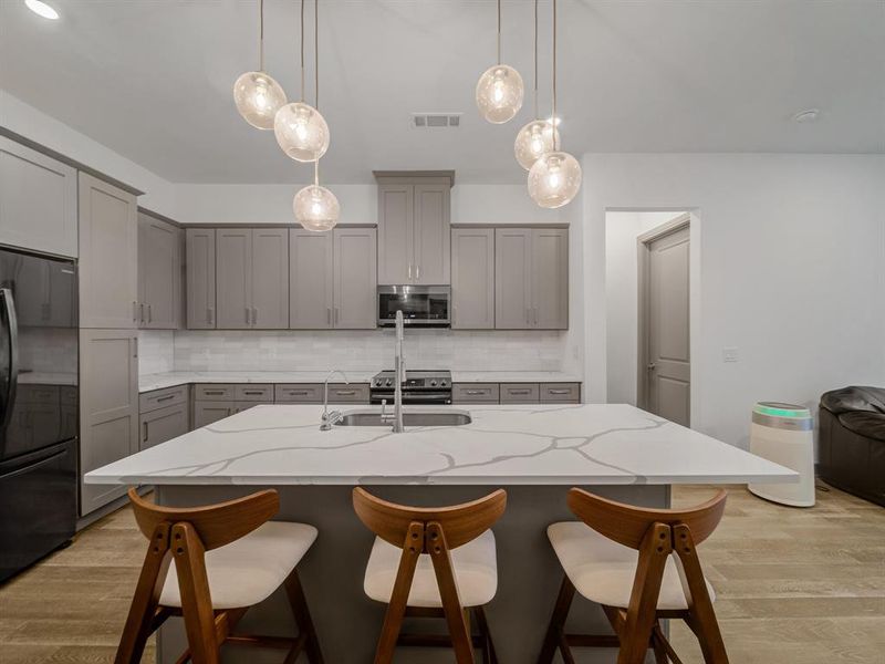 Kitchen featuring gray cabinetry, light wood finished floors, and stainless steel appliances