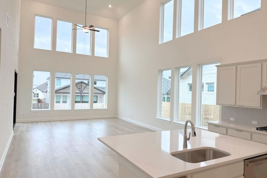 Kitchen with light stone counters, open floor plan, light wood finished floors, stainless steel dishwasher, and tasteful backsplash