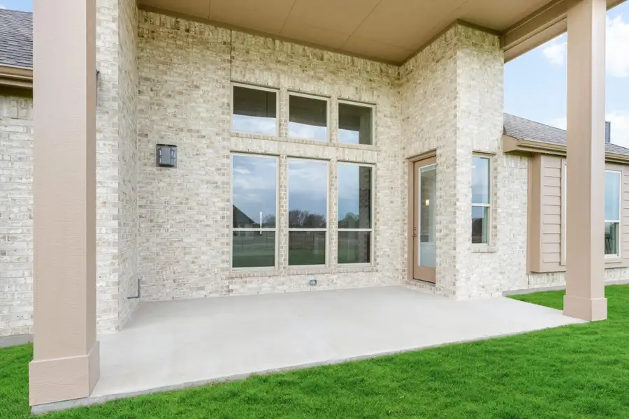 Covered back patio with concrete floor, light brick exterior, large windows, and a back door entry. Covered back patio with concrete floor, light brick exterior, large windows, and a back door entry.