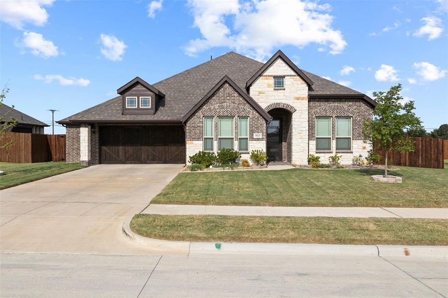 French country inspired facade with a front yard and a garage