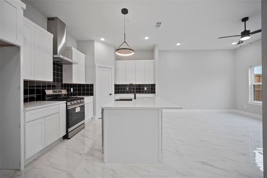 Kitchen with visible vents, stainless steel range with gas cooktop, marble finish floor, wall chimney exhaust hood, and a sink