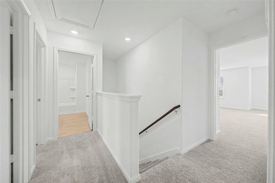 Corridor with an upstairs landing, light colored carpet, and recessed lighting