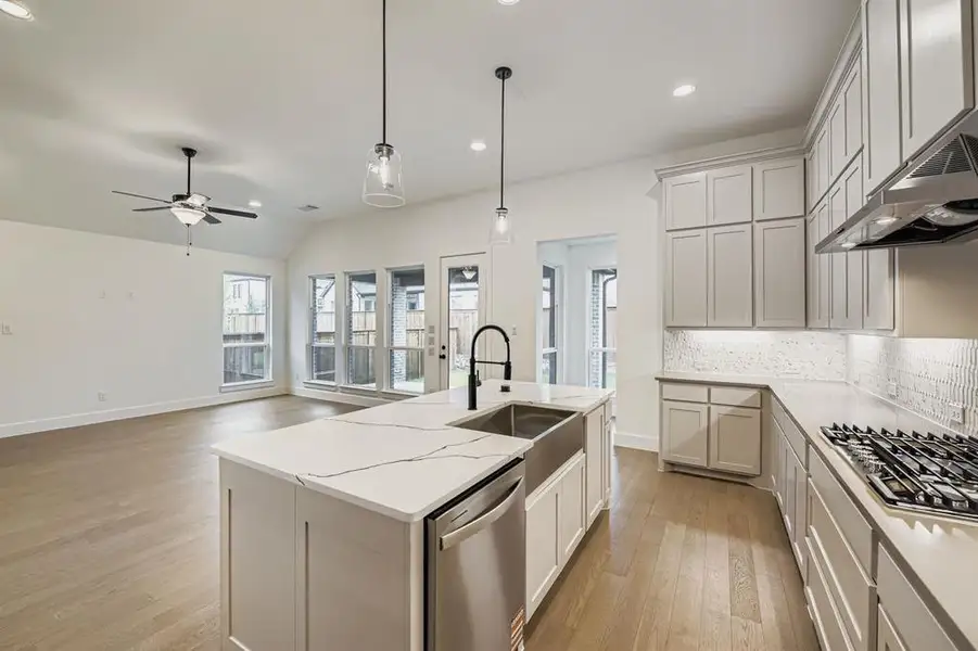 Kitchen with hanging light fixtures, appliances with stainless steel finishes, tasteful backsplash, light wood finished floors, and ceiling fan