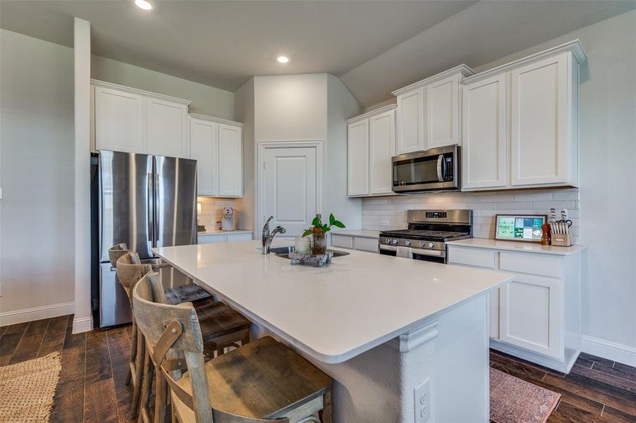 Kitchen with appliances with stainless steel finishes, white cabinetry, and wood like tile.