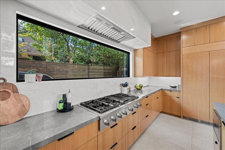 Kitchen featuring modern cabinets, stainless steel gas stovetop, recessed lighting, light brown cabinets, and dark stone counters