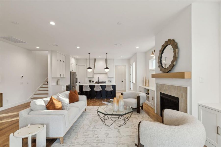 Living room with a tiled fireplace and light hardwood / wood-style flooring