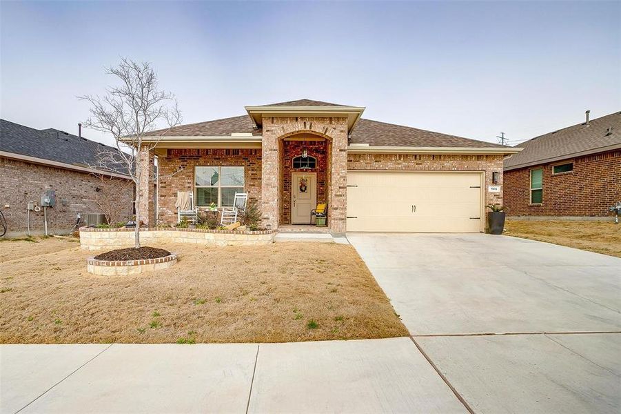 View of front facade with brick siding, driveway, an attached garage, and roof with shingles