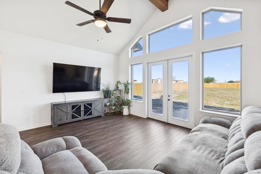 Living area with high vaulted ceiling, french doors, wood finished floors, ceiling fan, and healthy amount of natural light Living area with high vaulted ceiling, french doors, wood finished floors, ceiling fan, and healthy amount of natural light