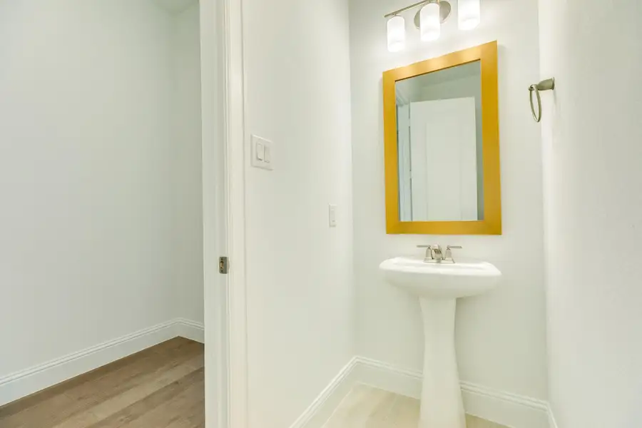 Half bath conveniently located on the main level, adjacent to the laundry room, featuring refined gold trim accents that match the home's elegant aesthetic.