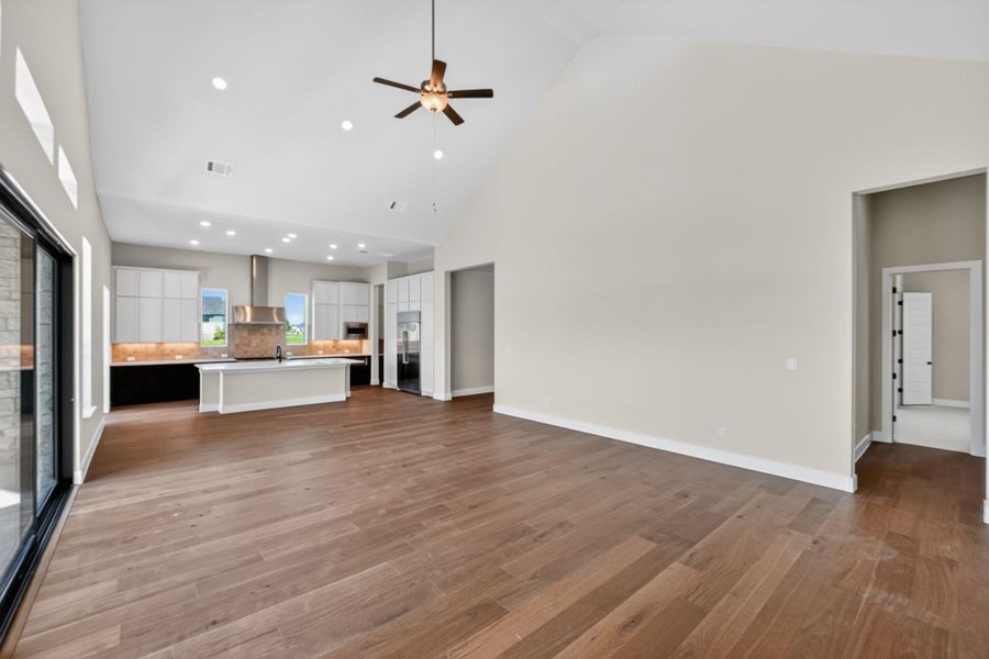 Unfurnished living room featuring high vaulted ceiling, light wood-type flooring, ceiling fan, and recessed lighting Unfurnished living room featuring high vaulted ceiling, light wood-type flooring, ceiling fan, and recessed lighting