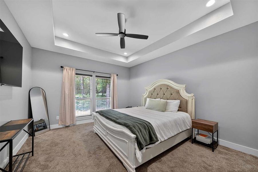 Bedroom with a raised ceiling, light carpet, ceiling fan, and recessed lighting Bedroom with a raised ceiling, light carpet, ceiling fan, and recessed lighting