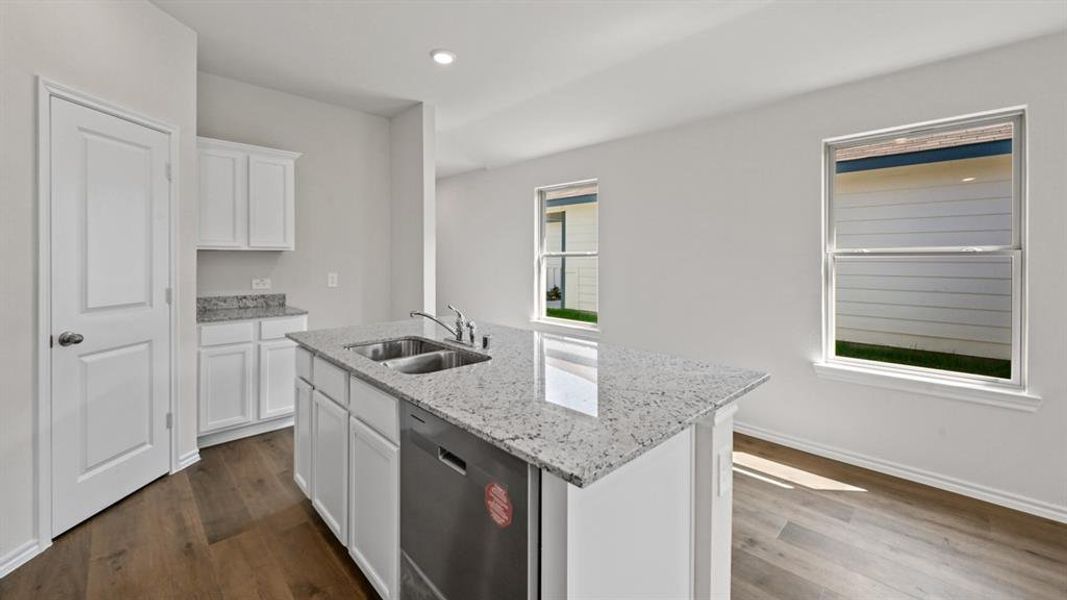 Kitchen island with a double basin sink, stainless steel dishwasher, and a speckled countertop