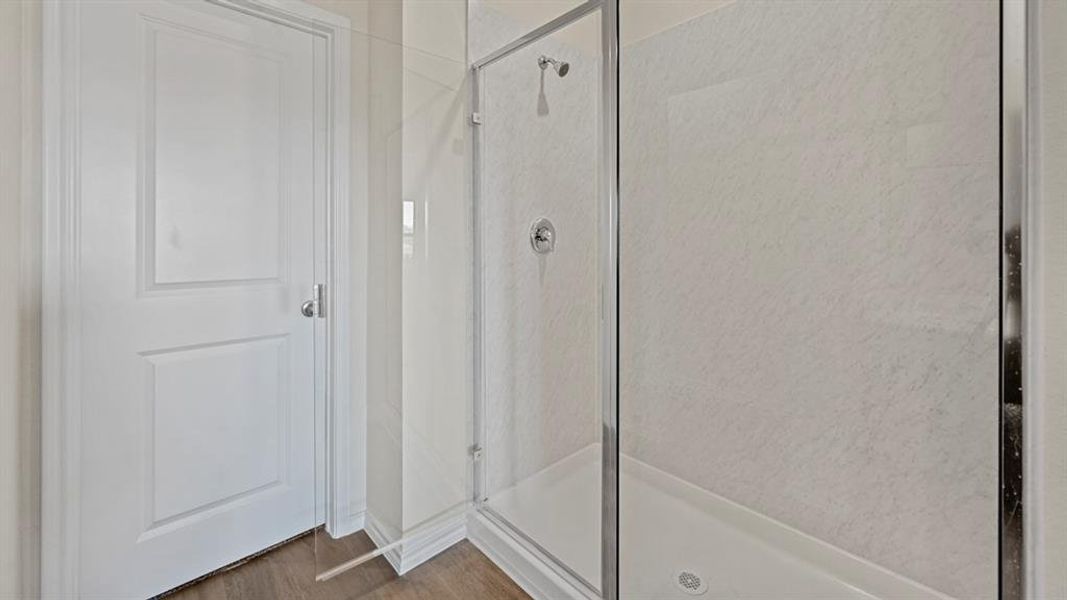 Shower with clear glass enclosure, chrome fixtures, and light-toned tile surround