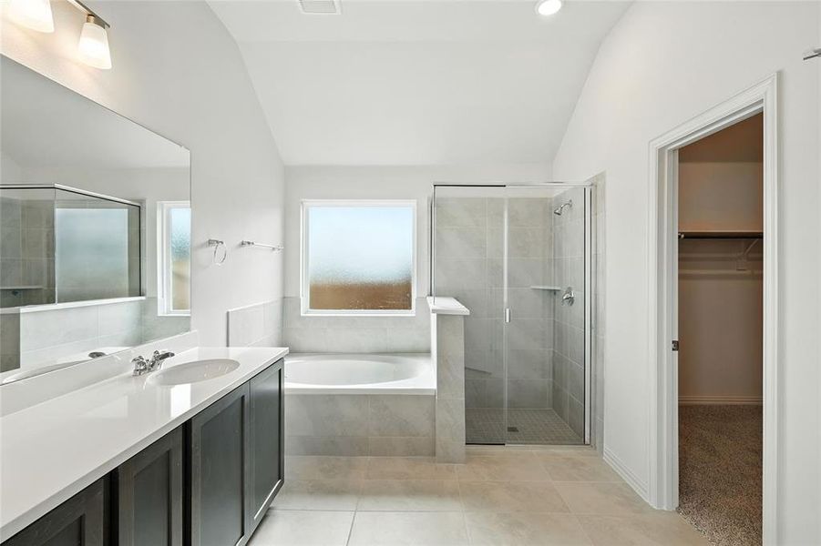 Bathroom featuring a walk in closet, vanity, a garden tub, a shower stall, and light tile patterned floors Bathroom featuring a walk in closet, vanity, a garden tub, a shower stall, and light tile patterned floors