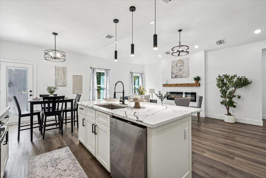 Kitchen featuring white cabinets, pendant lighting, and an island with sink