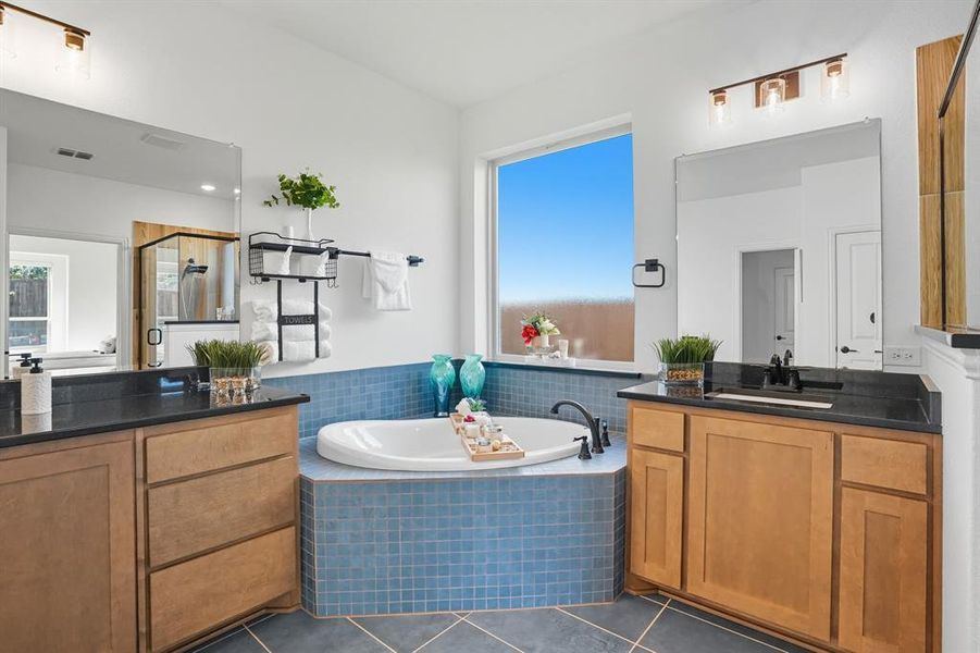 Full bathroom with dark tile patterned floors, a shower stall, a garden tub, and vanity
